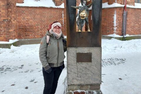 Wiebke steht in Riga neben einer Statue.